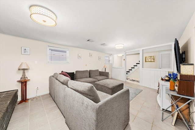 living room featuring light tile patterned floors, visible vents, stairway, and a wealth of natural light