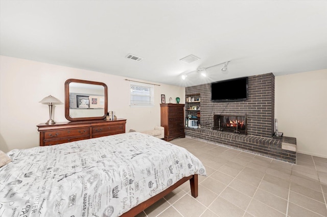 bedroom with tile patterned flooring, visible vents, a fireplace, and rail lighting