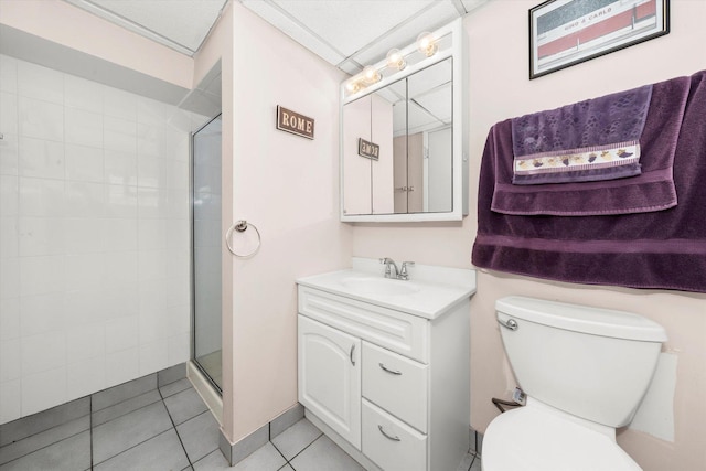 bathroom featuring tile patterned flooring, tiled shower, vanity, and toilet