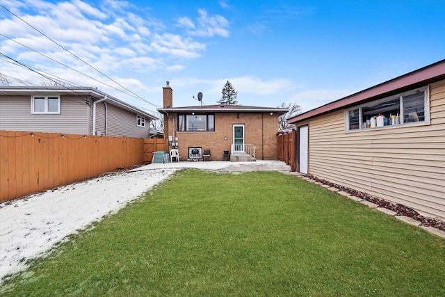 rear view of house with entry steps, a lawn, a chimney, and a fenced backyard