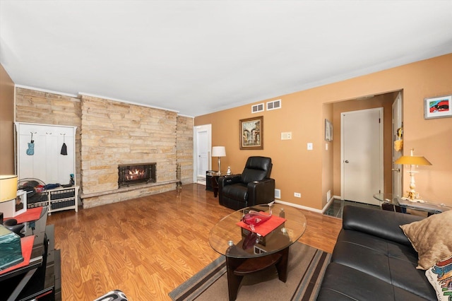 living room featuring baseboards, a fireplace, visible vents, and wood finished floors