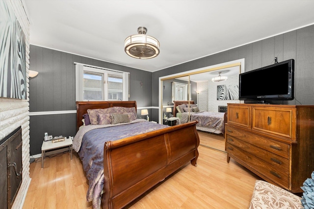 bedroom featuring a closet, a fireplace, and light wood-style flooring