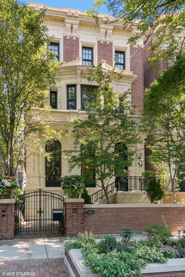 italianate house featuring a gate, brick siding, and fence