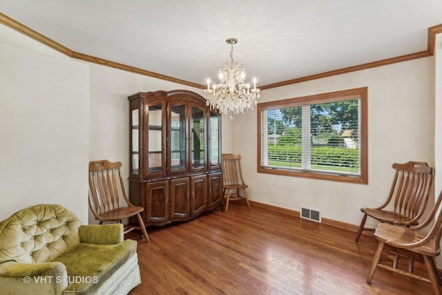 sitting room with a chandelier, visible vents, crown molding, and wood finished floors