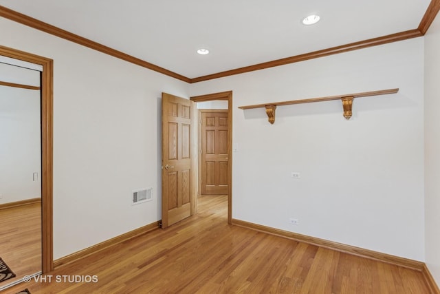 spare room with light wood-style floors, visible vents, and ornamental molding