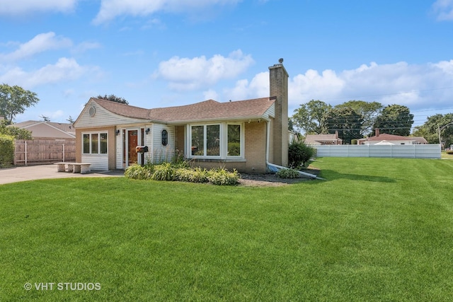 view of front of house with a patio, brick siding, fence, a front lawn, and a chimney