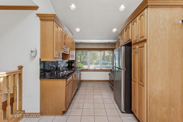 kitchen with light tile patterned flooring, stainless steel appliances, a sink, dark stone counters, and tasteful backsplash