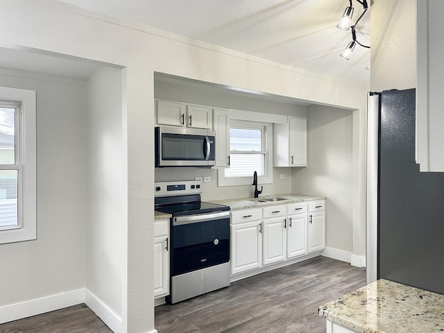 kitchen featuring appliances with stainless steel finishes, dark wood-type flooring, a sink, and white cabinetry