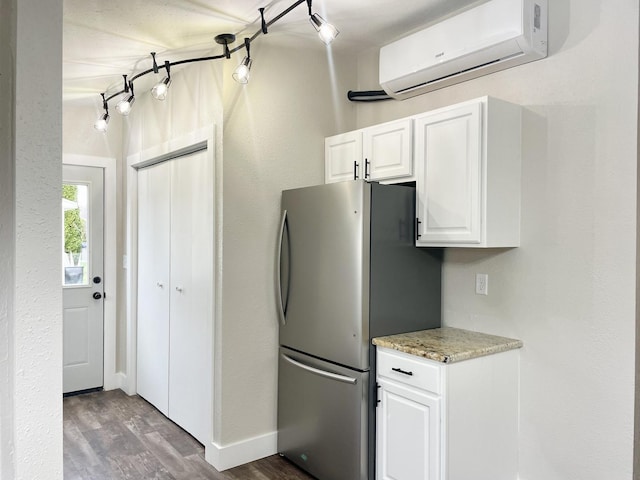 kitchen featuring light stone counters, wood finished floors, white cabinetry, freestanding refrigerator, and a wall mounted air conditioner