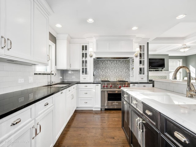 kitchen featuring dark stone countertops, white cabinetry, premium range, and a sink