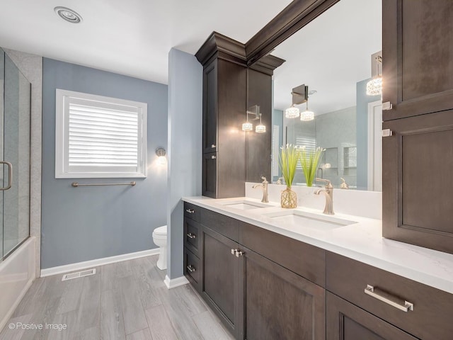 bathroom with visible vents, a sink, toilet, and wood finished floors