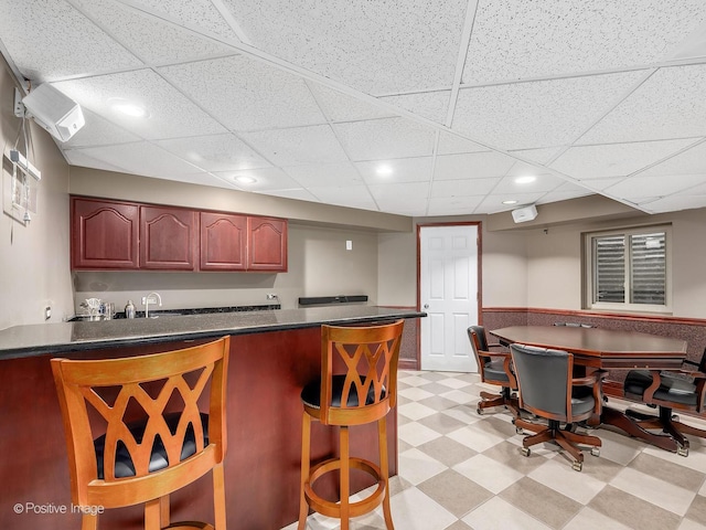 kitchen featuring dark countertops, a peninsula, light floors, a kitchen bar, and recessed lighting