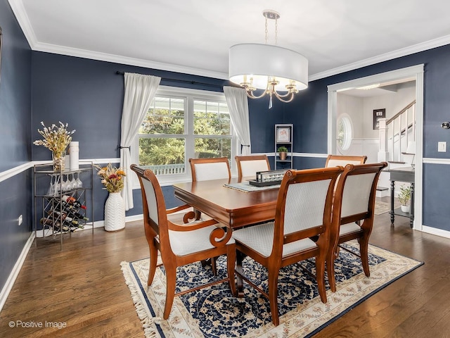 dining room with a wainscoted wall, ornamental molding, wood finished floors, stairs, and a notable chandelier