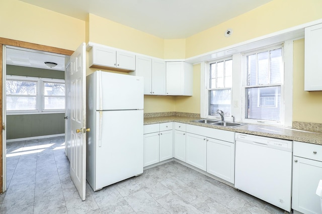 kitchen with plenty of natural light, white cabinets, white appliances, and a sink