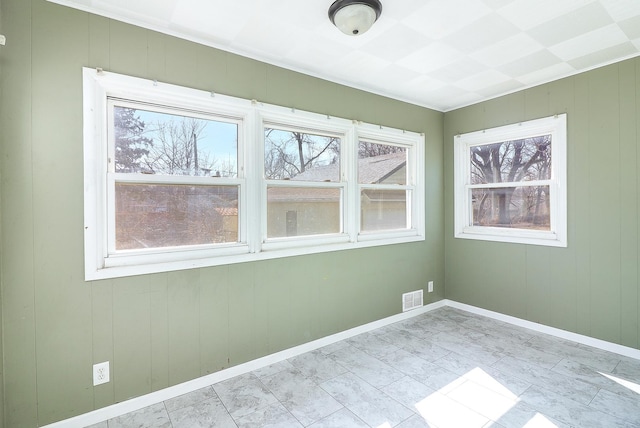 empty room featuring a healthy amount of sunlight, visible vents, and baseboards