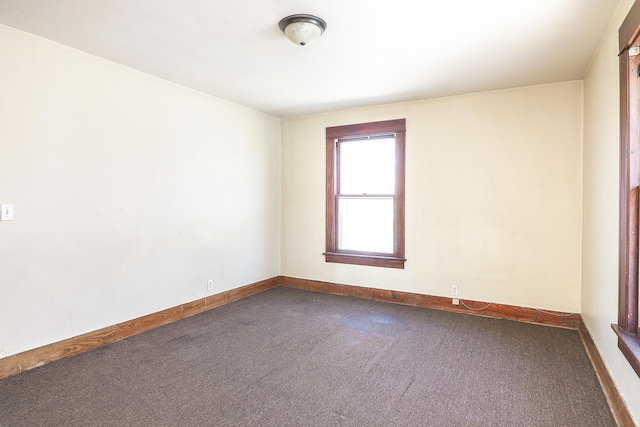 empty room with baseboards and dark carpet