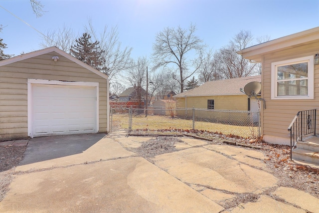 detached garage featuring concrete driveway and fence