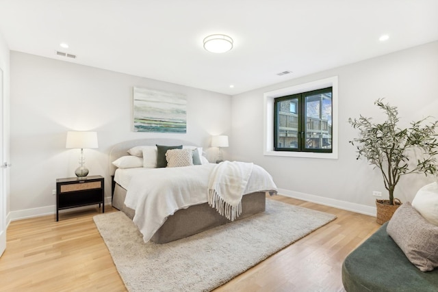 bedroom featuring light wood finished floors, visible vents, and baseboards