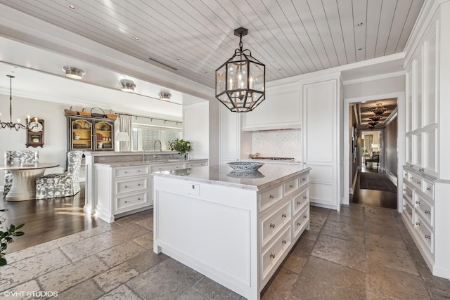 walk in closet featuring an inviting chandelier, a sink, and stone tile floors