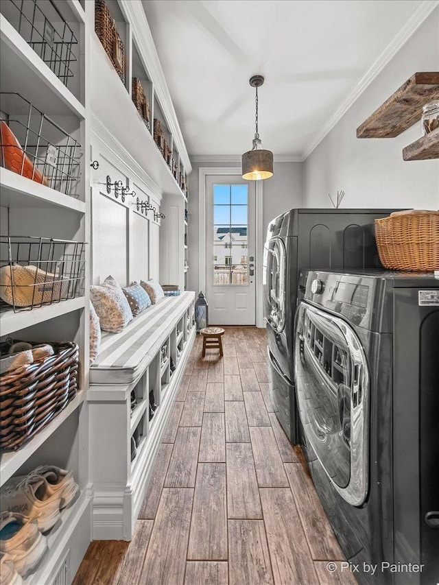 clothes washing area with laundry area, separate washer and dryer, crown molding, and wood finish floors