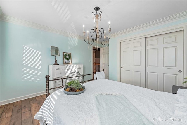 bedroom with baseboards, dark wood-style floors, an inviting chandelier, crown molding, and a closet