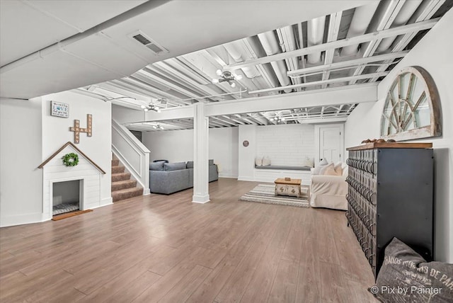 living room with stairway, a fireplace, wood finished floors, and visible vents