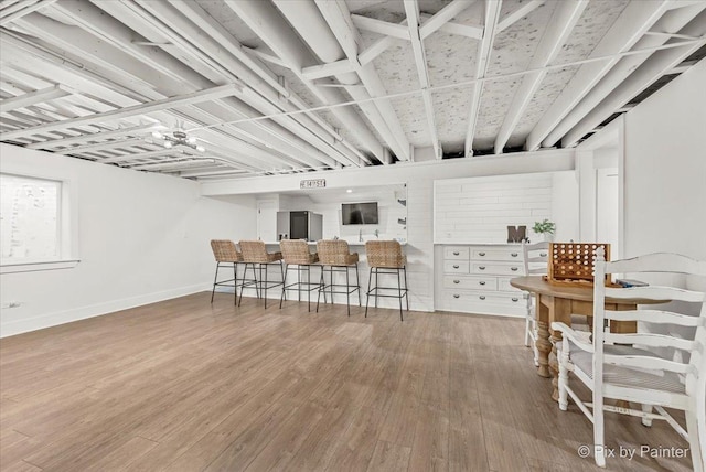 kitchen featuring baseboards, wood finished floors, and stainless steel fridge with ice dispenser