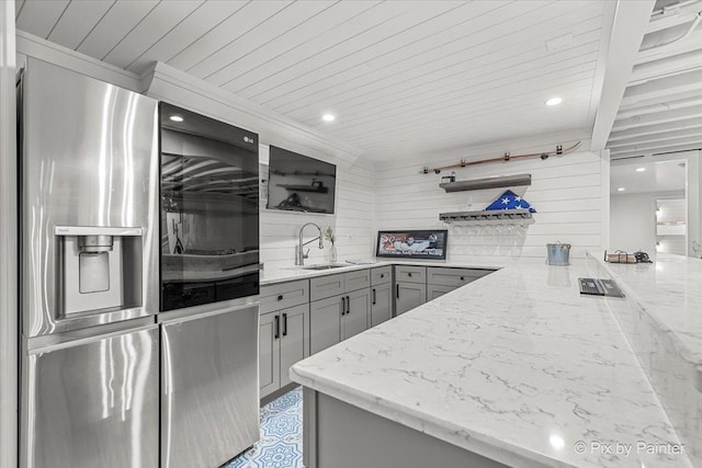 kitchen featuring open shelves, gray cabinets, a sink, light stone countertops, and stainless steel fridge with ice dispenser