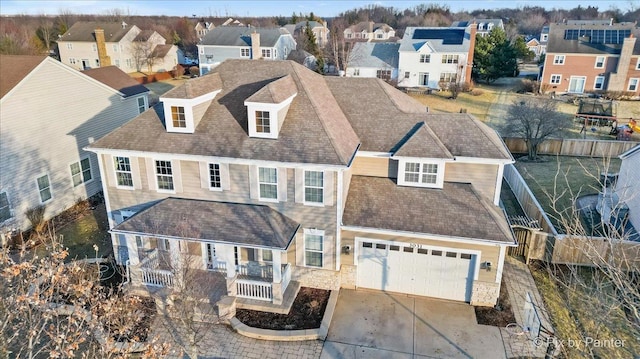 view of property with a shingled roof, a residential view, fence, and concrete driveway