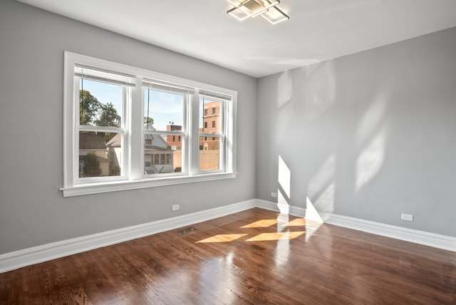 spare room featuring baseboards and wood finished floors