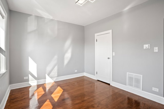 empty room featuring baseboards, visible vents, and wood finished floors