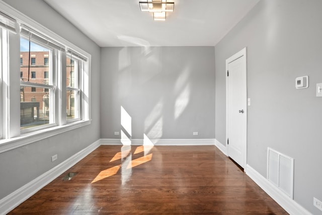 empty room featuring visible vents, baseboards, and wood finished floors