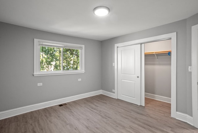 unfurnished bedroom featuring a closet, baseboards, and wood finished floors