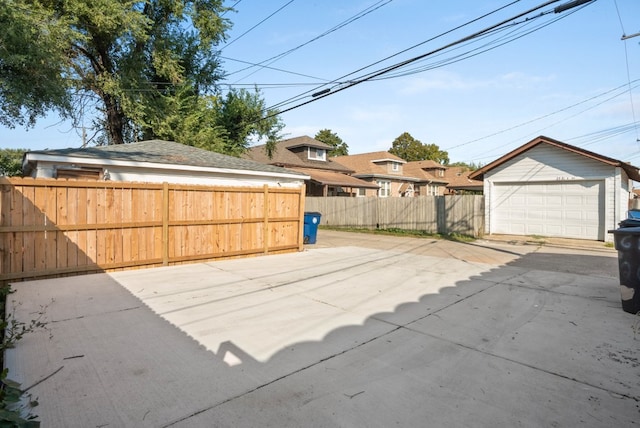 view of patio featuring a detached garage, fence, and an outbuilding