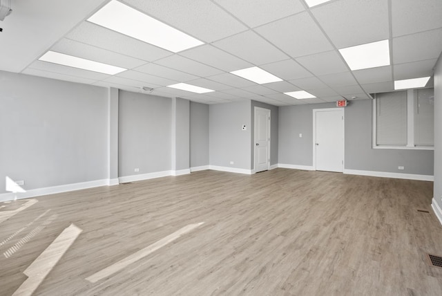 interior space with a paneled ceiling, baseboards, and wood finished floors