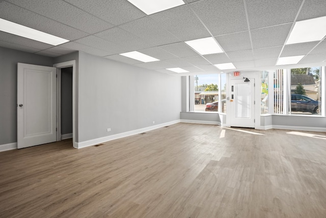 unfurnished room featuring a drop ceiling, wood finished floors, visible vents, and baseboards