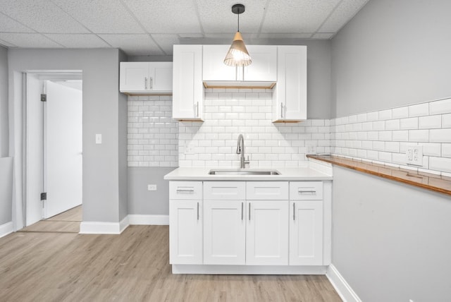 kitchen with light wood finished floors, a sink, and white cabinets