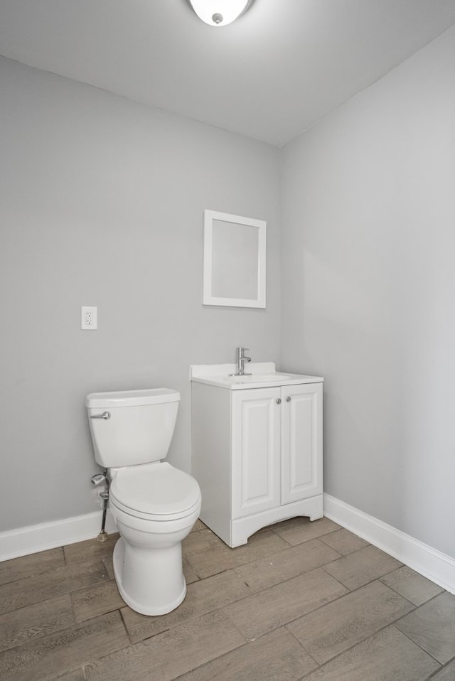 bathroom with a sink, wood finished floors, toilet, and baseboards