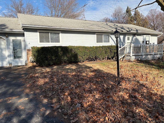 view of side of home featuring a deck and a shingled roof