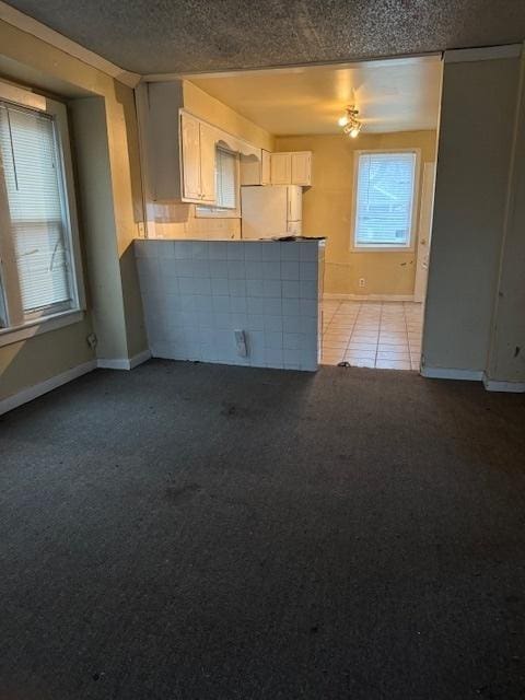 220 N Sumner Ave, Aurora, IL 60505 - unfurnished living room with light carpet, baseboards, light tile patterned floors, and a textured ceiling