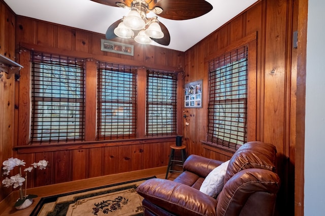 sitting room featuring wood walls and a ceiling fan