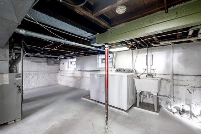 below grade area featuring a sink, washer and clothes dryer, and heating unit