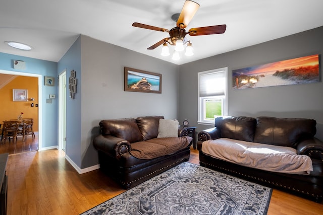 living room with ceiling fan, baseboards, and wood finished floors