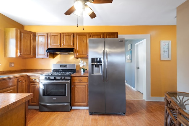 kitchen with appliances with stainless steel finishes, brown cabinets, and under cabinet range hood