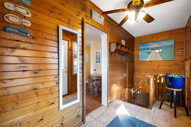 interior space featuring tile patterned flooring, wood walls, and ceiling fan