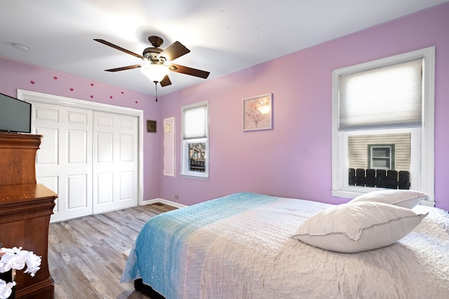 bedroom featuring a ceiling fan, a closet, baseboards, and wood finished floors