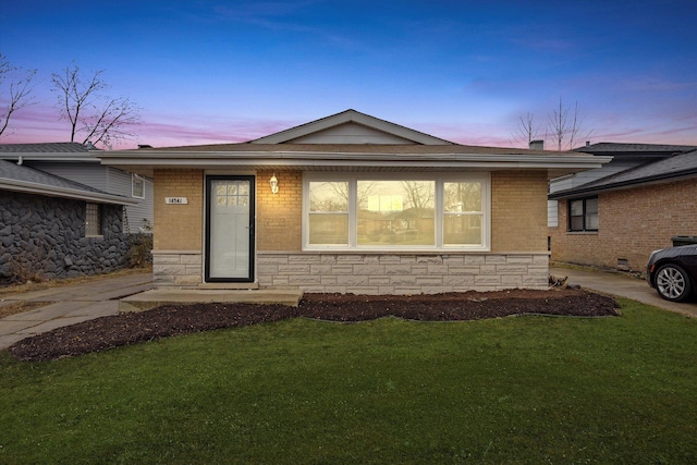 single story home with stone siding and a yard