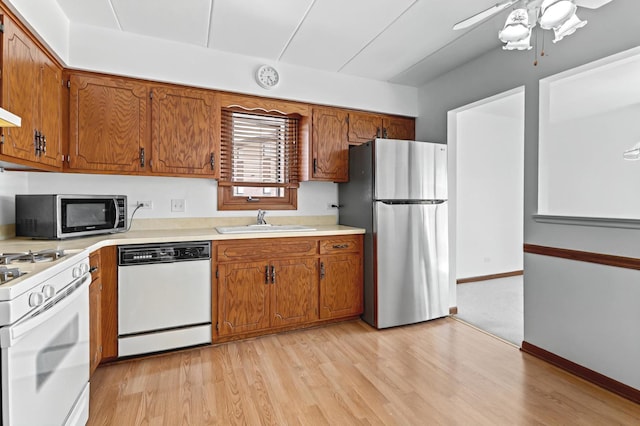 kitchen with stainless steel appliances, brown cabinets, light countertops, and a sink