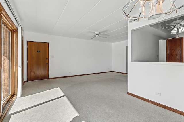 carpeted empty room featuring baseboards and ceiling fan with notable chandelier