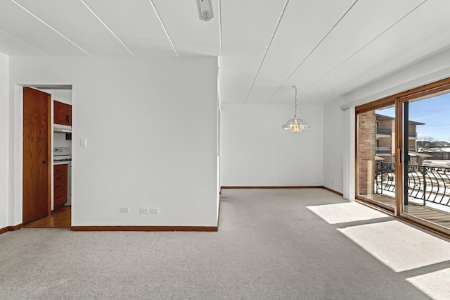 carpeted empty room with an inviting chandelier and baseboards